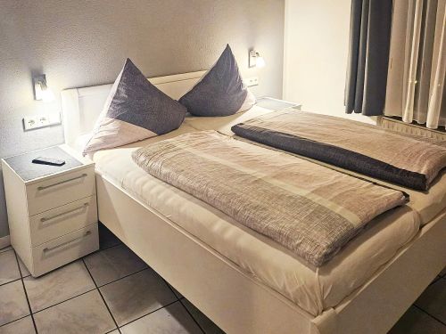 Modernes Schlafzimmer mit Doppelbett zwei Kissen und Nachttisch mit Fernbedienung