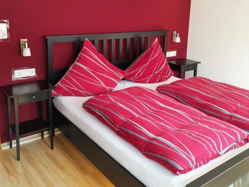 Schlafzimmer mit roter Wand und Bett mit roten Bettdecken und schwarzen Nachttischen